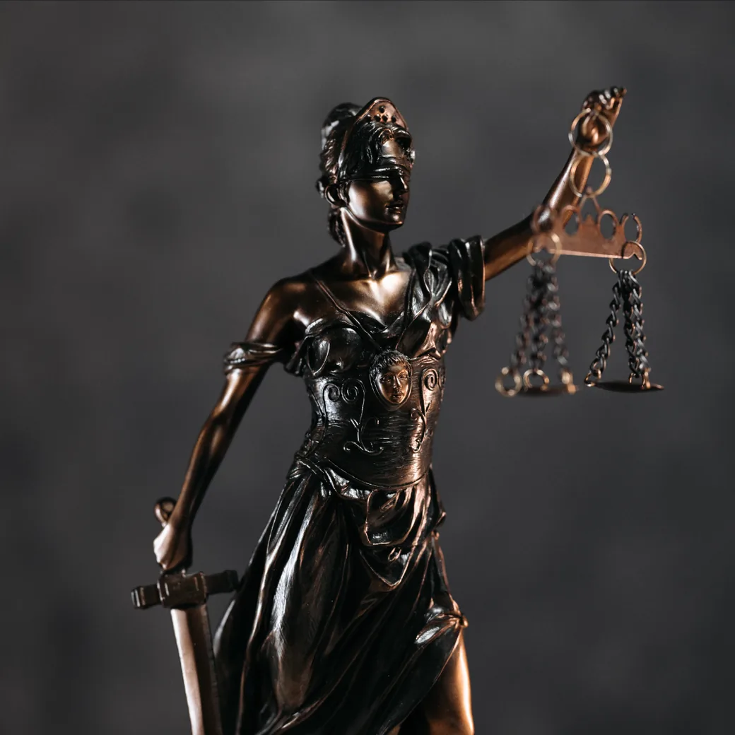 Estatua de bronce de la justicia, con los ojos vendados, sosteniendo la balanza en alto y la espada al costado